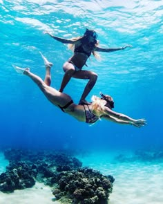 two women in bikinis are diving under the water