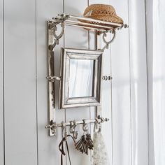 a mirror hanging on the side of a white wall next to a hat and other items