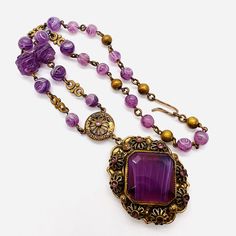 "Gorgeous vintage WEST GERMANY purple slag glass beaded necklace. Ornate gilt metal set with center purple slag glass stone surrounded by flowerette settings with amethyst rhinestones and on purple slag glass beaded necklace. Pendant measures 2 5/8 inches tall at the heart and 1 1/2 inches wide. The glass beaded chain is 3/8 inch wide at widest point. Total length is 17 inches long. Signed \"West Germany\" on hook clasp. Hook and dangle clasp secure. Excellent vintage condition with minimal age Purple Beaded Vintage Necklace, Purple Vintage Beaded Necklace, Vintage Purple Beaded Necklace, Vintage Gemstone Beaded Necklaces For Jewelry Making, Handmade Antique Purple Jewelry, Vintage Purple Pendant Necklace, Handmade Vintage Amethyst Jewelry, Antique Handmade Purple Jewelry, Purple Amethyst Necklace For Collectors