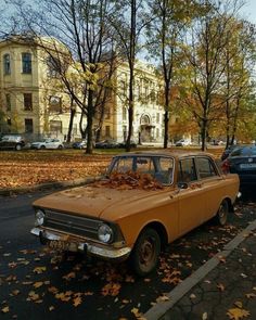 an old car is parked on the side of the road with leaves all over it