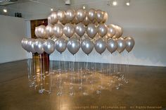 a bunch of balloons floating in the air on top of a metal table with water droplets