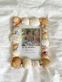 a photo frame made out of seashells on a white sheet with the words keep best and water written in it