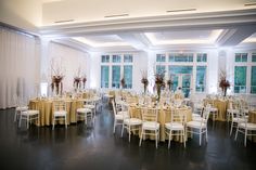 a banquet hall with tables and chairs covered in gold cloths, decorated with tall centerpieces