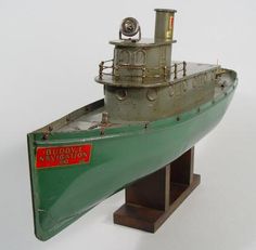 a green model boat sitting on top of a wooden stand