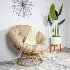 a round chair sitting on top of a white rug next to a potted plant