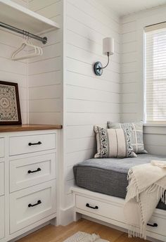 a bedroom with white painted walls and wood flooring, built - in storage drawers