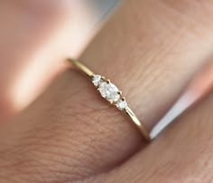 a woman's hand with a diamond ring on top of her finger, showing the side view