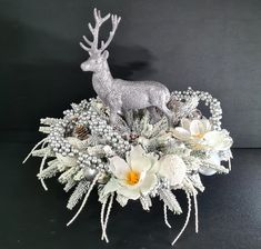 a silver deer with white flowers and pine cones