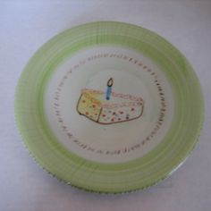 a green and white plate with a piece of cake painted on the side, sitting on a table