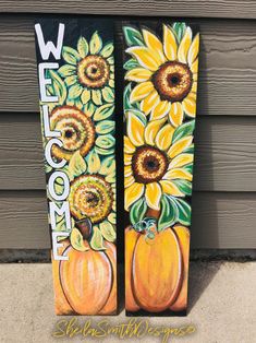 two painted pumpkins and sunflowers are sitting on the side of a building