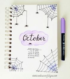 a spiral notebook with the word october written on it next to a purple marker and spider web