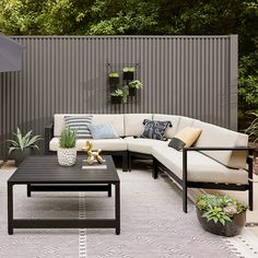 an outdoor living area with couches, tables and potted plants