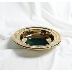 a gold and green dish on a white sheet