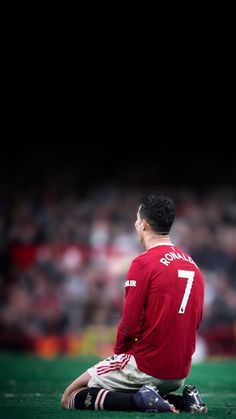 a man sitting on the ground in front of a crowd wearing a red shirt and white shorts