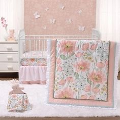 a baby crib bedding set with pink flowers and butterflies on the wall next to it