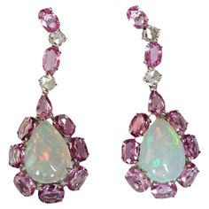 A very gorgeous and beautiful, Opal & Pink Sapphires Chandelier Earrings set in 18K White Gold & natural Diamonds. The weight of the Ethiopian Opals is 6.12 carats. The weight of the Pink Sapphires is 7.60 carats. The Pink Sapphires are of Ceylon (Sri Lanka) origin. The Diamonds weight is 0.64 carats. Net 18K White Gold weight is 7.20 grams. The Gross weight of the Earrings is 10.06 grams. The dimensions of the Earrings are 4.30cm x 1.60cm x 1.00cm (L x W x D). The Earrings have a push back. Fea Luxury Pink Opal Round Jewelry, Luxury Pink Halo Setting Earrings, Luxury Multicolor Temple Jewelry Earrings, Luxury Ethiopian Opal Teardrop Jewelry, Earring Video, Diamond Chandelier Earrings, Diamond Chandelier, Ceylon Sri Lanka, Ethiopian Opal Ring