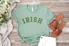 A simple & modern St Patricks Day graphic tee for women or men, perfect for celebrating the Irish holiday or giving as a St Patricks gift for a wife, sister or friend. Features a minimalistic green and yellow gold arched "IRISH" text design printed on our cozy heather sage green gender neutral crew neck tee. Made from quality, buttery-soft airlume cotton that provides all day comfort, breathability & durability. ☑ 52% airlume cotton + 48% polyester☑ Buttery-soft, light-weight & breathable materi Casual Green Top As Gift, Green Casual Top, Graphic Tee T-shirt As Gift In Green, Crew Neck T-shirt With Lettering For Gift, Green T-shirt With Text Print For Everyday, Green Letter Print Top As Gift, Green Tops With Screen Print For Gift, Green Letter Print Top As A Gift, Green Screen Print Top As Gift