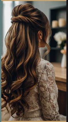 a woman with long hair sitting in front of a mirror wearing a white dress and gold earrings