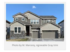 a large gray house with two garages in the front and one on the side