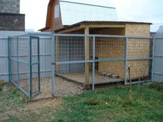 a small chicken coop in the middle of a yard next to a building with a metal roof