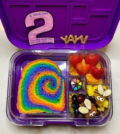 a lunch box filled with fruit, candy and other items to make a rainbow cake