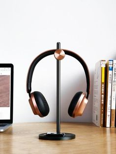 headphones on a stand next to a laptop computer and bookshelf in front of a white wall