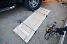 a car is parked next to a ramp made out of wooden planks and wires