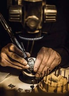 a man is working on a watch in front of a clock and some other tools