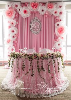 a pink and white wedding backdrop with flowers on the side, monogrammed table