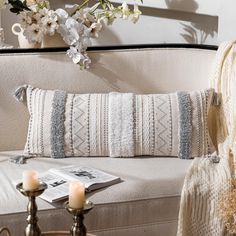 a white couch sitting next to a table with two candles on it and flowers in the background