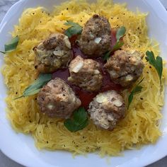 meatballs with sauce and parsley on top of yellow spaghetti in a white bowl