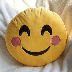 a yellow smiley face pillow sitting on top of a white bed sheet with pink eyes