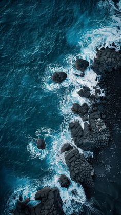 an aerial view of the ocean and rocks