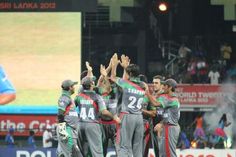 a group of men standing next to each other on top of a baseball field with their hands in the air