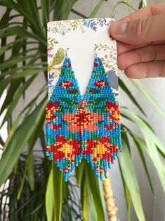 a pair of colorful beaded earrings hanging from a plant