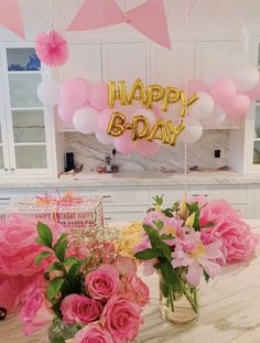 some pink flowers and balloons on a table