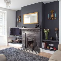 a living room with gray walls and a fireplace in the center, decorated with gold accents