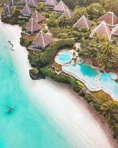 an aerial view of a beach resort with boats in the water and trees surrounding it