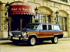 an old station wagon parked in front of a hotel