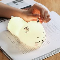 a person holding a small white elephant shaped keychain on top of a book