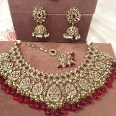 Beautiful antique gold necklace set with dazzling champagne zircon crystals and maroon stones. Plus maroon glass beads. Perfect bridal set Comes with matching jhumka earrings and matching tikka! Necklace 3 inch with adjustable string Earrings 2.25 Inch including jhumka length x 1 inch width Tikka 2.5 inch pendant plus 2 inch chain and 2 inch extender chain  Ready to be shipped ❤️ Red Jeweled Bridal Necklace For Wedding, Gold Chandbali Bridal Necklace Jeweled, Gold Chandbali-shaped Jeweled Bridal Necklace, Gold Chandbali Bridal Necklace With Jeweled Details, Red Stone Wedding Necklaces, Festive Crystal Jewelry Sets With Stone Work, Ornate Kundan Jewelry For Party, Festive Kundan Necklace With Crystal Stone Work, Ruby Jeweled Necklaces For Wedding