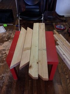 several pieces of wood sitting on top of a red table next to a black chair