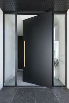 an open door leading into a room with white walls and black tiles on the floor