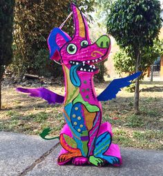 a colorful dragon statue sitting on top of a cement slab in front of some trees