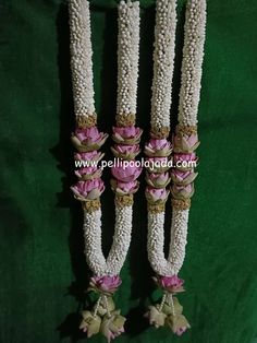 three white and pink flowers are attached to some kind of beads on a green cloth