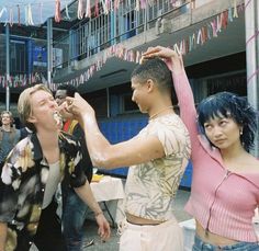 a man is getting his hair combed by two women in front of an apartment building