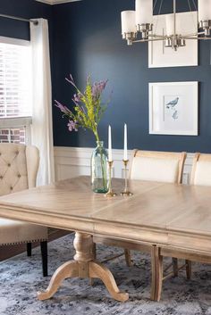 a dining room table with chairs and a vase filled with flowers on top of it