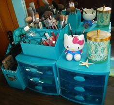 a hello kitty toy sitting on top of a blue dresser next to other makeup products