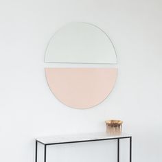 a table with a vase and mirror on it in front of a wall mounted round mirror