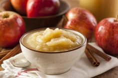 a bowl filled with pudding sitting on top of a table next to apples and cinnamon sticks